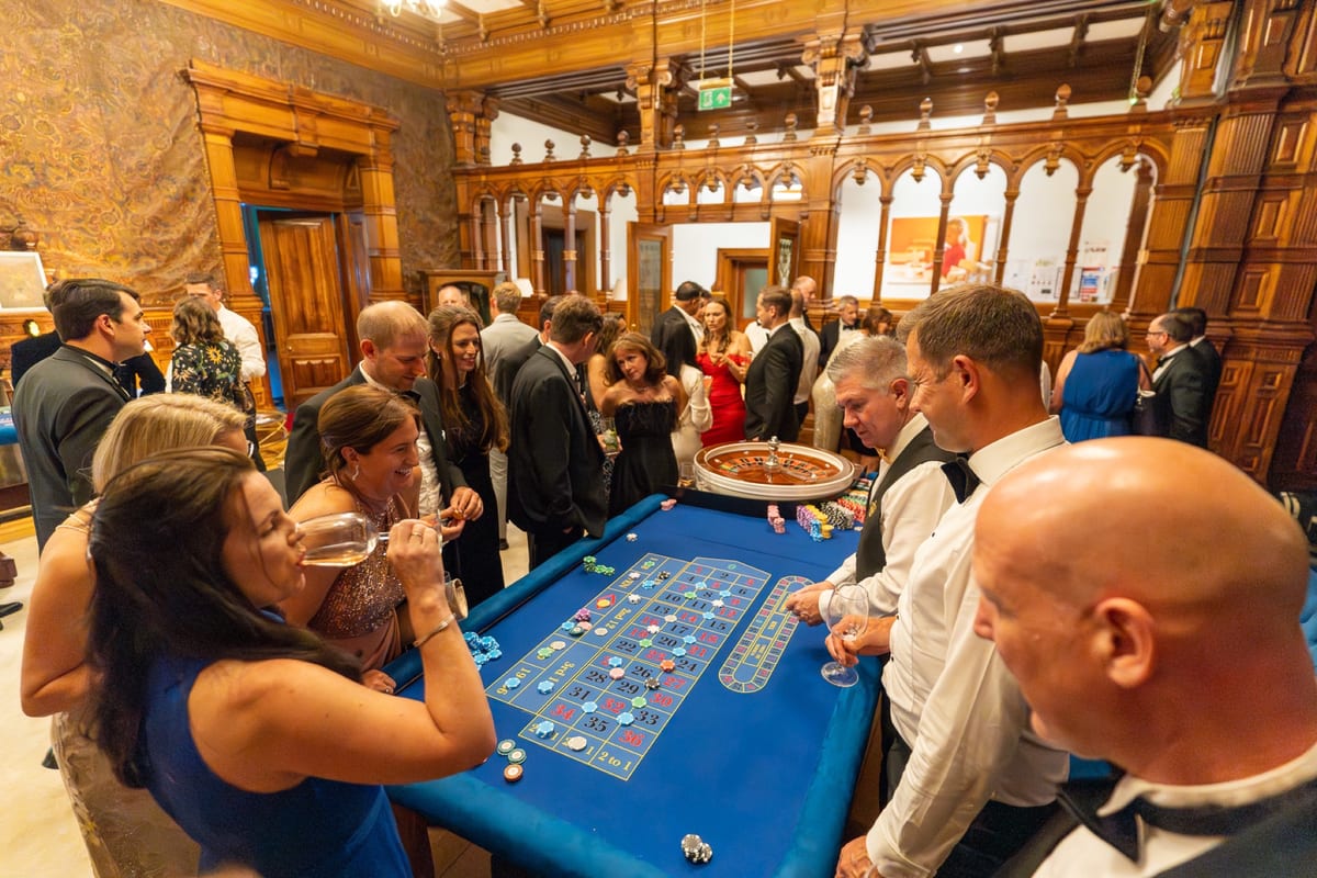 Guests gathered around a Royale Casino Hire roulette table at a corporate event in a wood-panelled London venue