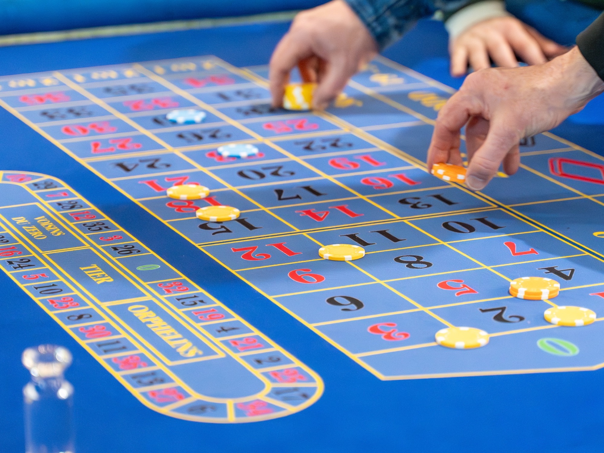 Guests' hands placing chips across a busy Royale table