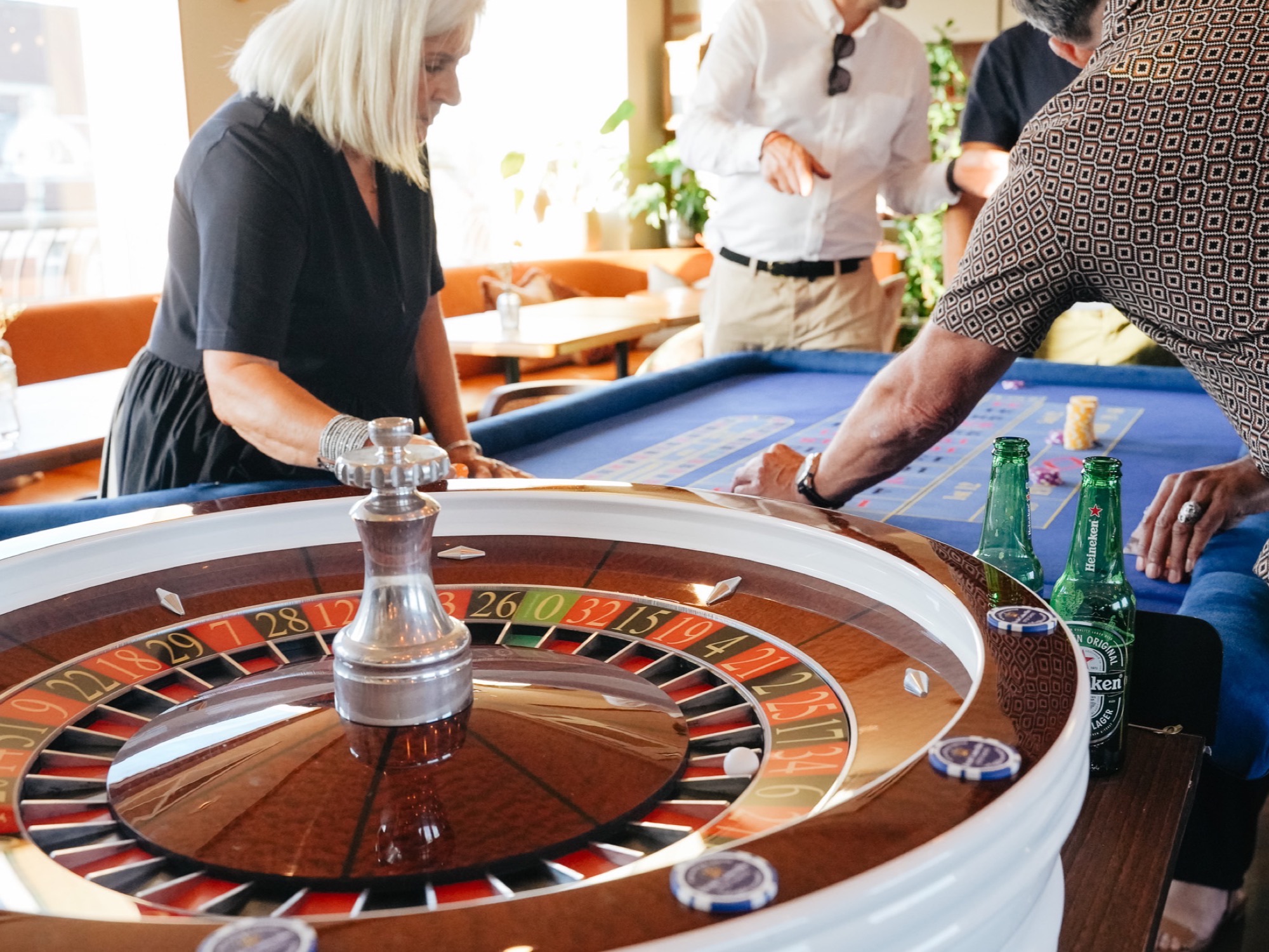A wooden roulette wheel in a sunlit hotel bar as guests place their chips