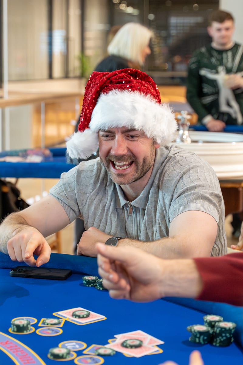 A guest in a Santa hat laughing at the Three Card Poker table