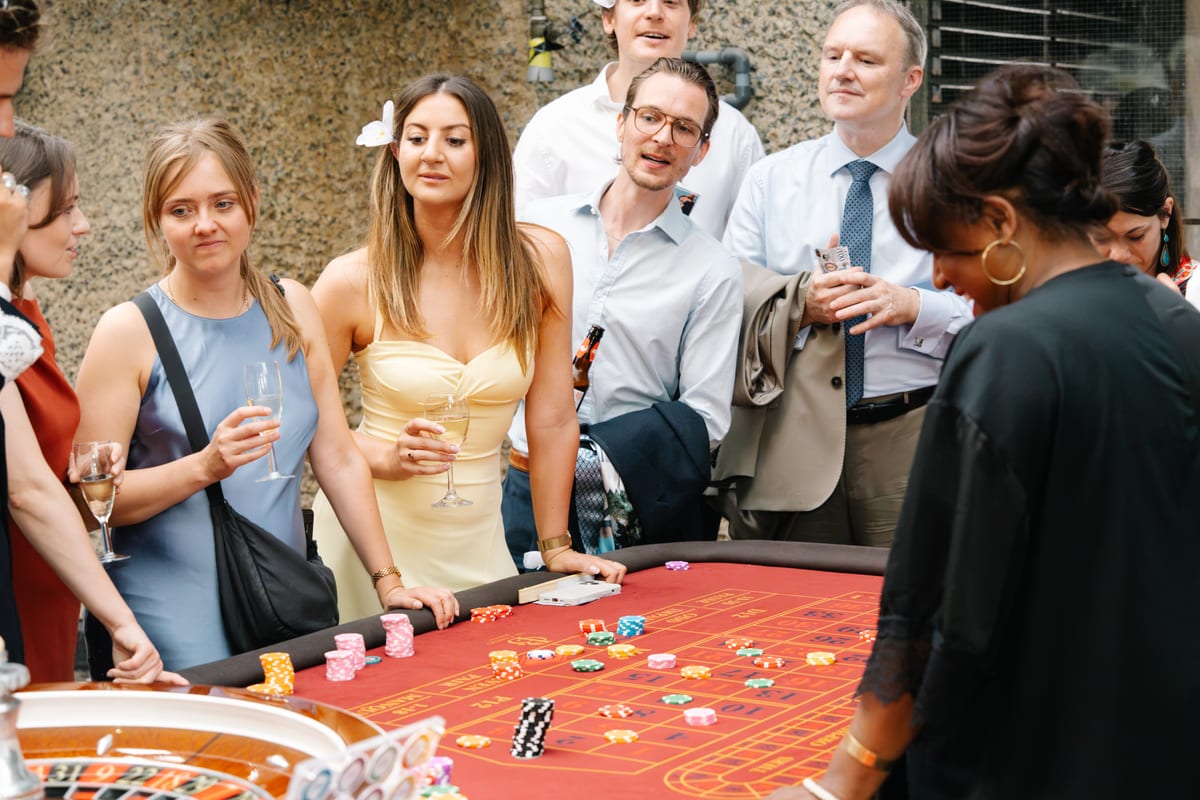 Guests laughing round a red roulette table at a daytime party