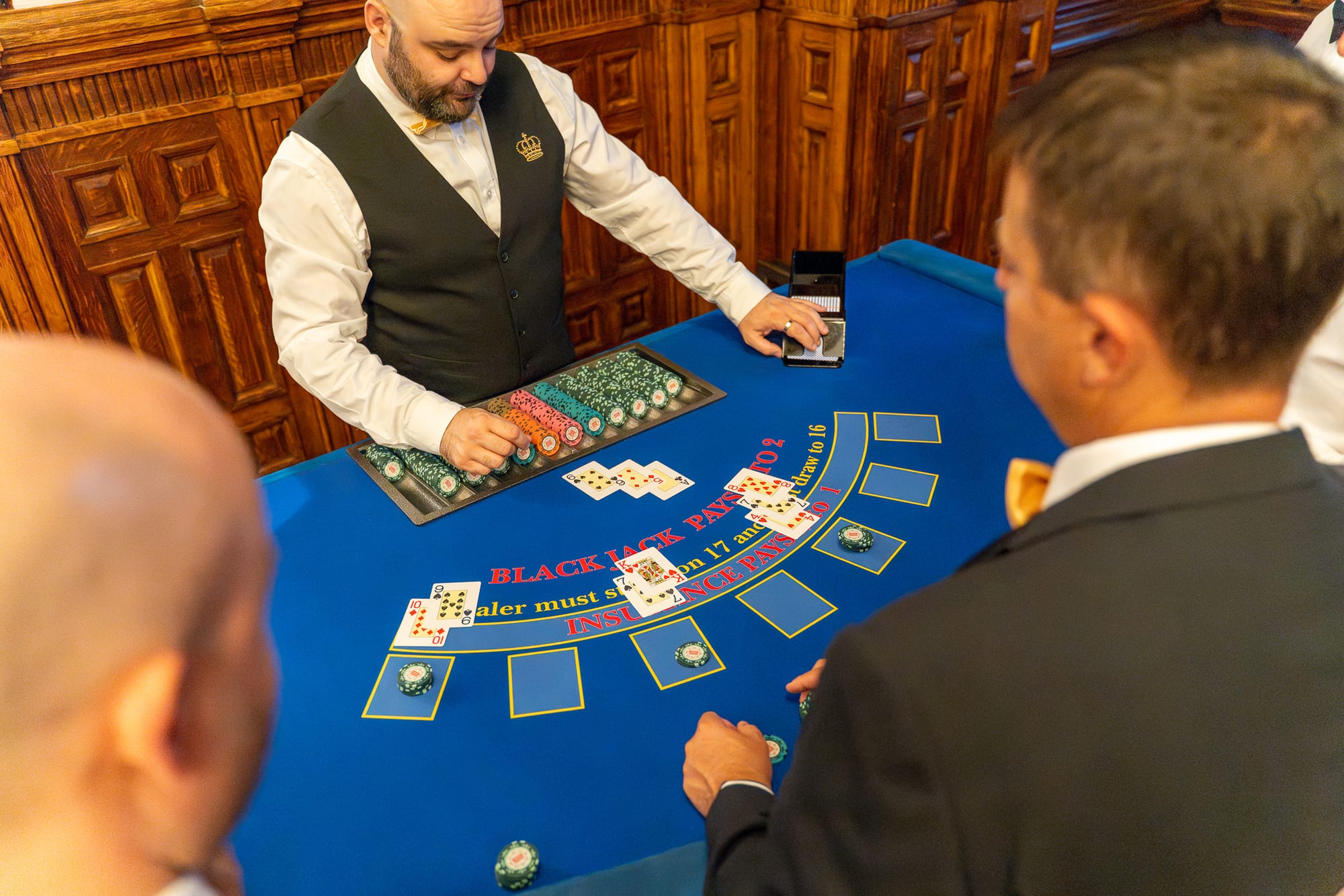 A Royale croupier dealing a hand of blackjack in an oak-panelled hall