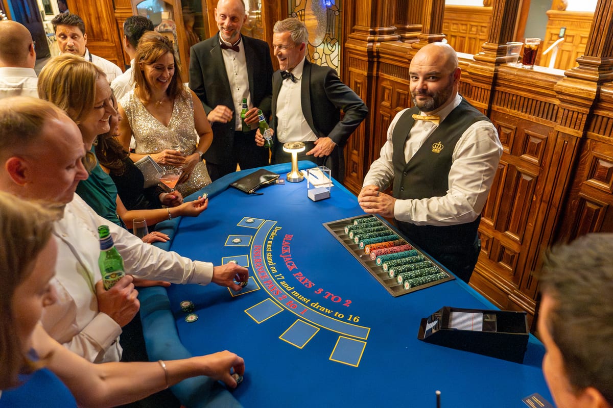 Guests in black tie gathered round a blackjack table with our croupier
