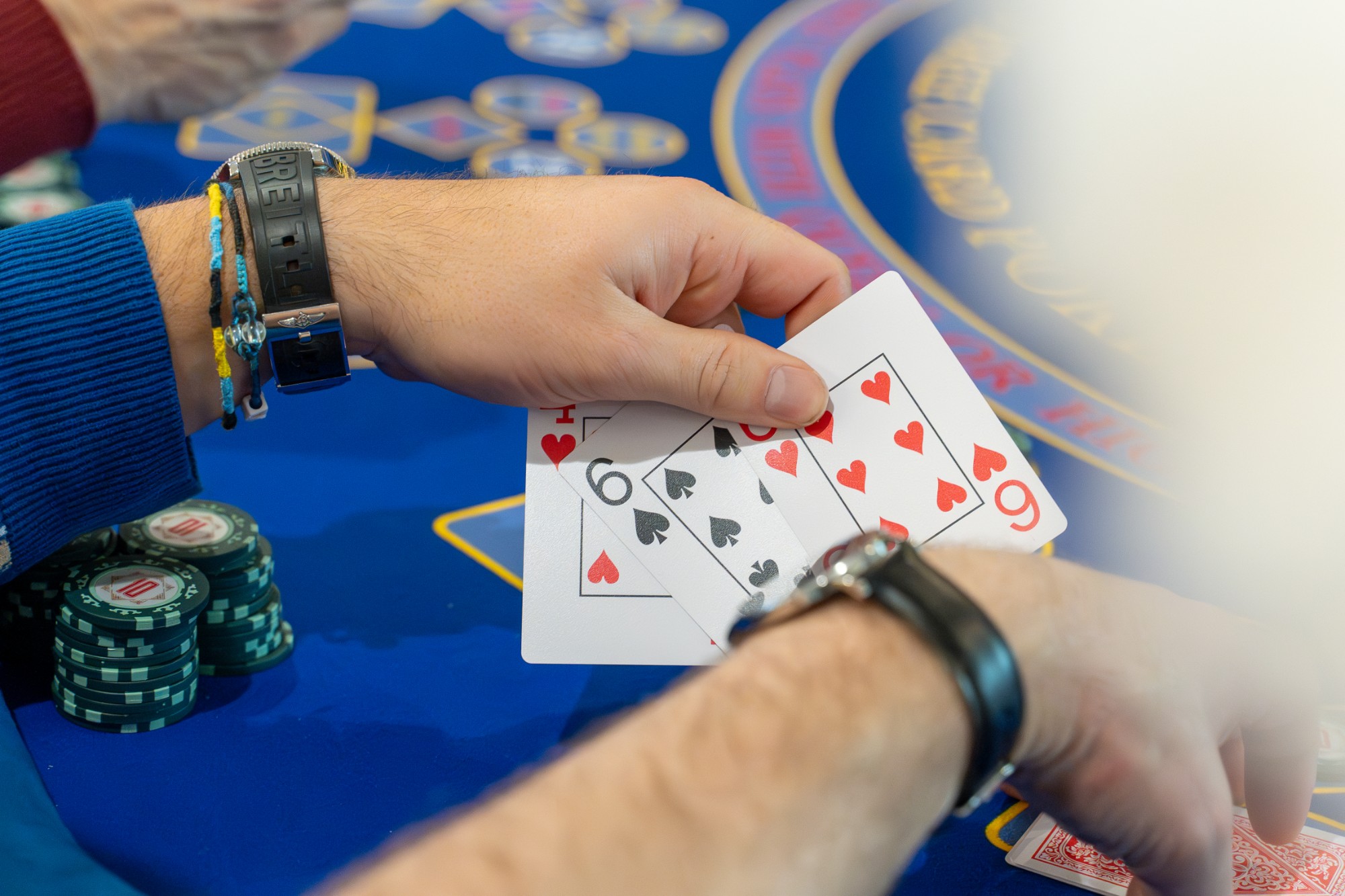 A player holding three cards over a Royale Teen Patti table, stacks of chips alongside